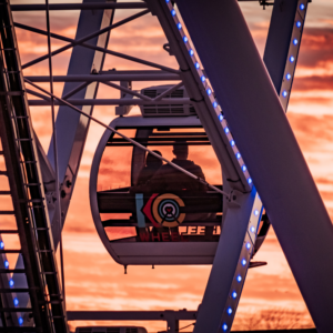 KC Wheel gondola with couple sitting inside against the orange sunset in the background